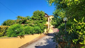 Un bâtiment jaune doté d’un balcon, entouré de verdure et surplombant un ciel bleu clair.