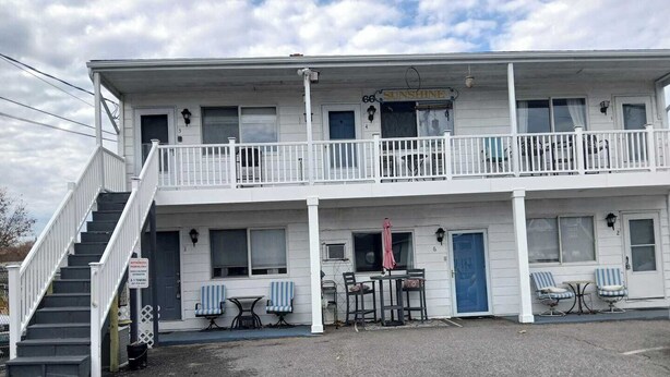 Ein zweistöckiges Motel mit Balkon, einer Treppe und einem Schild mit der Aufschrift 'Sunshine'.