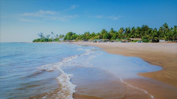 A beach with clear blue water, sandy shore, and palm trees in the background. - Jacks Calangute place (Calangute)