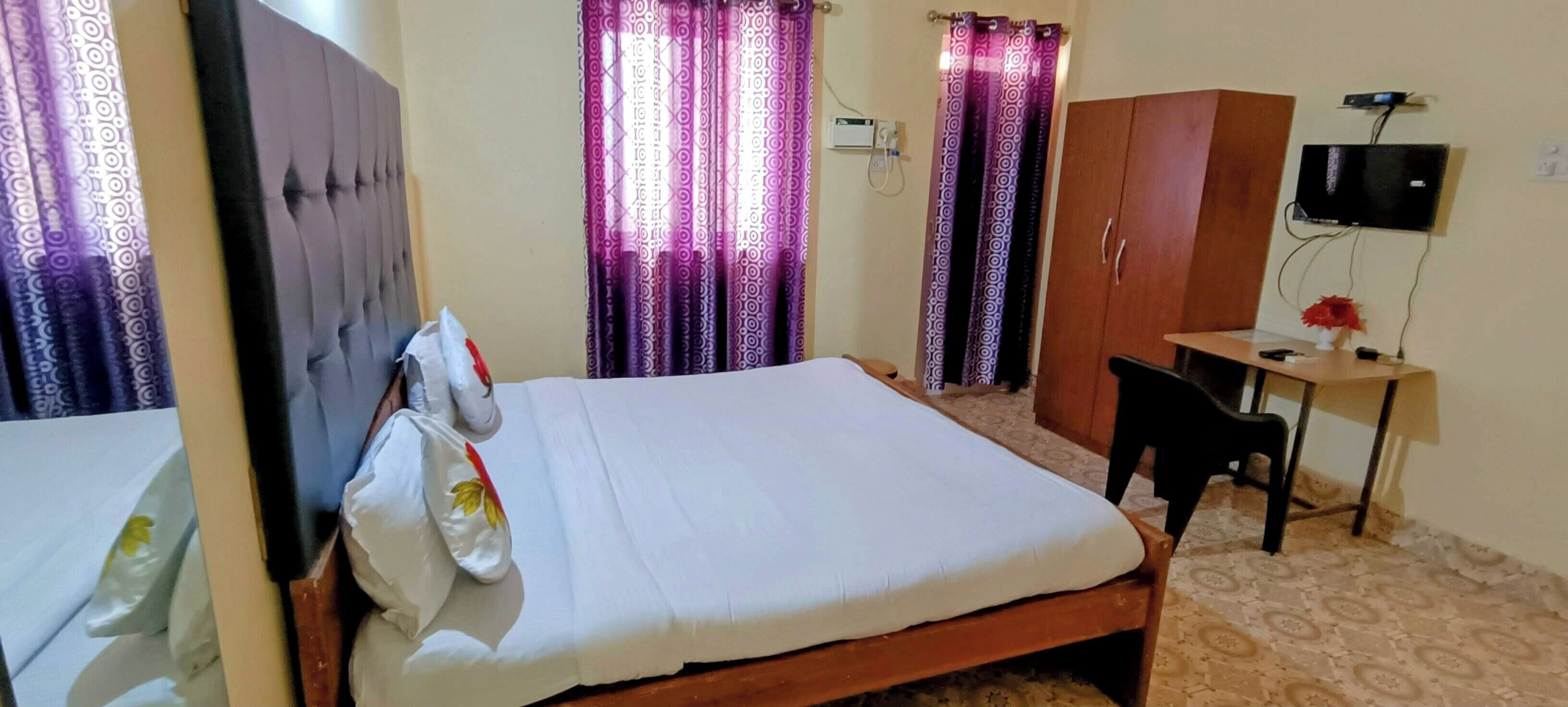 A hotel room with a bed, a desk, a TV, and a wardrobe.