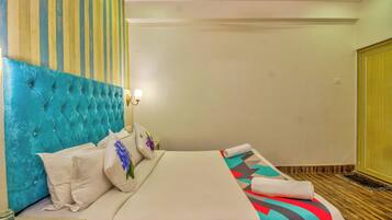 Een hotelkamer met een gestoffeerd hoofdeinde, een bed met een gestreept dekbed en een houten vloer.