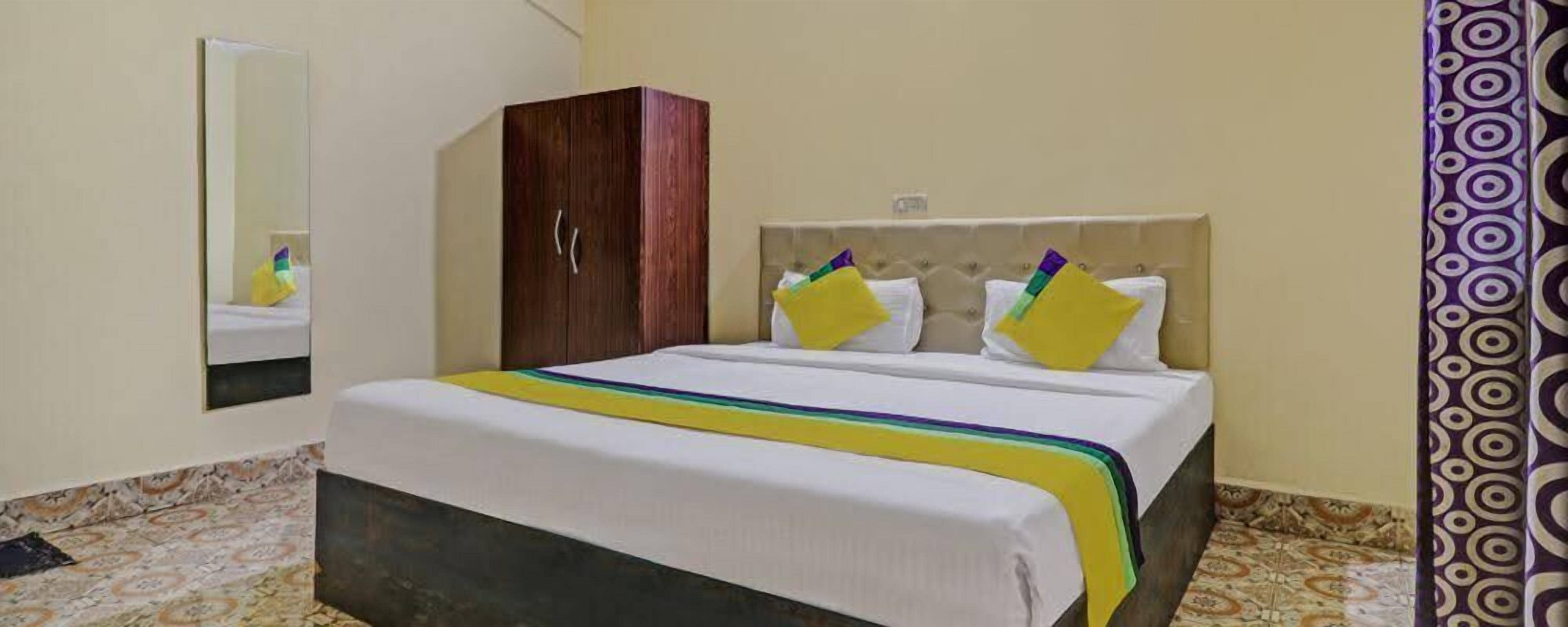 Una habitación de hotel con cama, armario, espejo y cortina estampada.