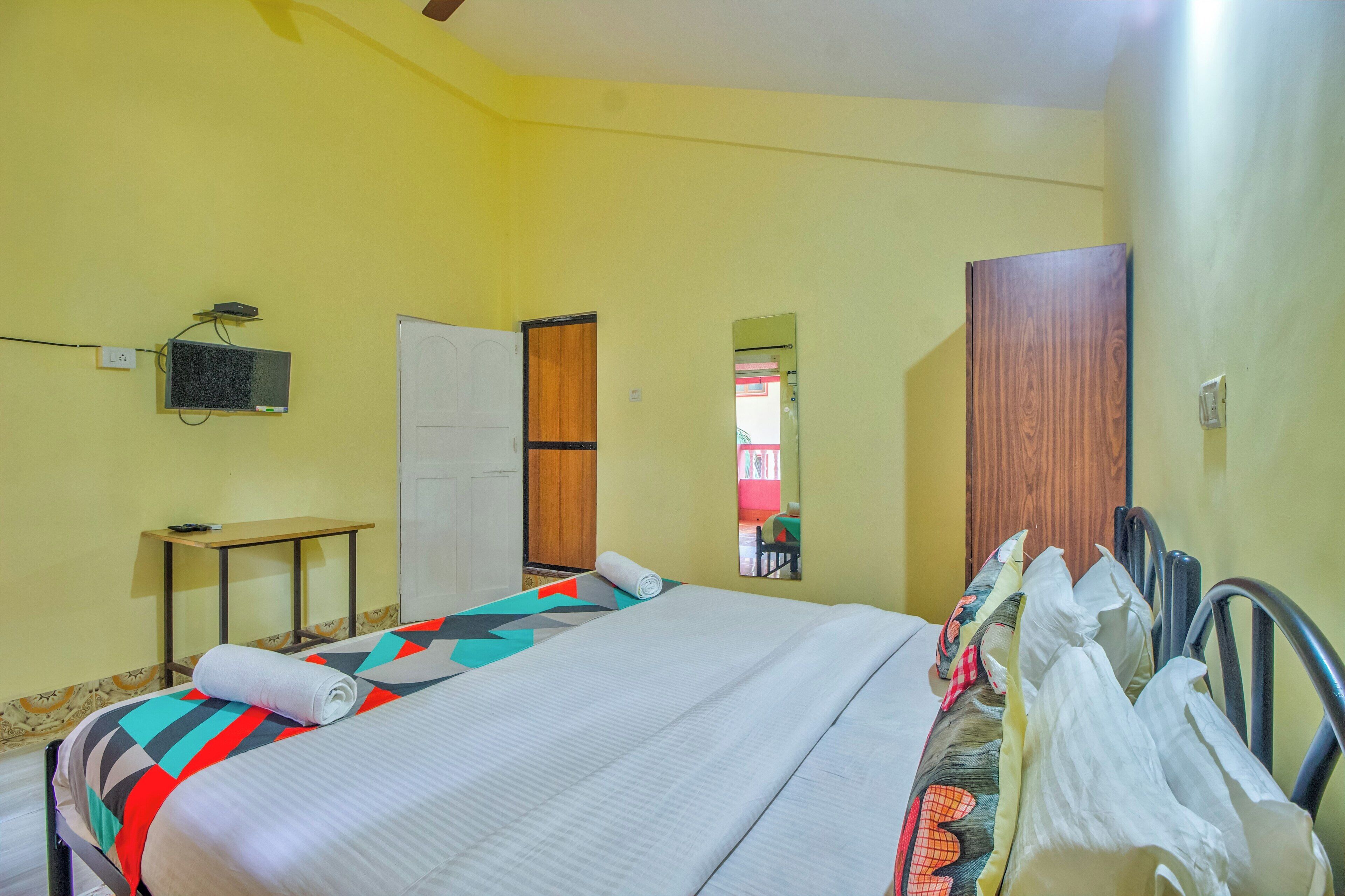 A hotel room with a bed, a desk, a television, and a wardrobe.