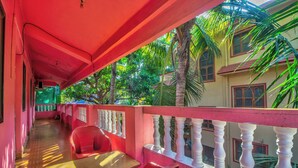 A corridor with a red and white balustrade, a table, and red chairs. - Jacks Calangute place (Calangute)