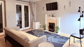 Een moderne woonkamer met een bank, een open haard, een flatscreen televisie en een eethoek.