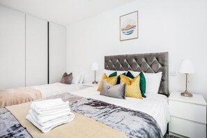 A hotel room with a bed, a bedside table with a lamp, a wardrobe, and a framed picture on the wall. - Cosy London Apartment Near River Thames (London)