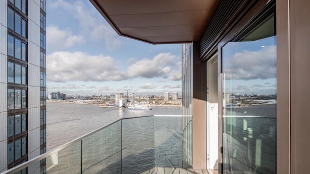 A balcony with a view of a river and cityscape. - Cosy London Apartment Near River Thames (London)