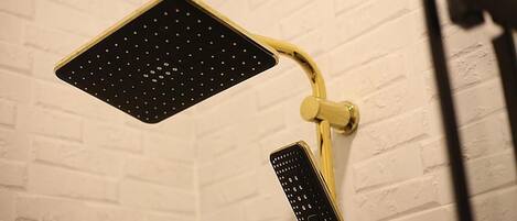 A shower with a black perforated panel and a gold-colored control panel.