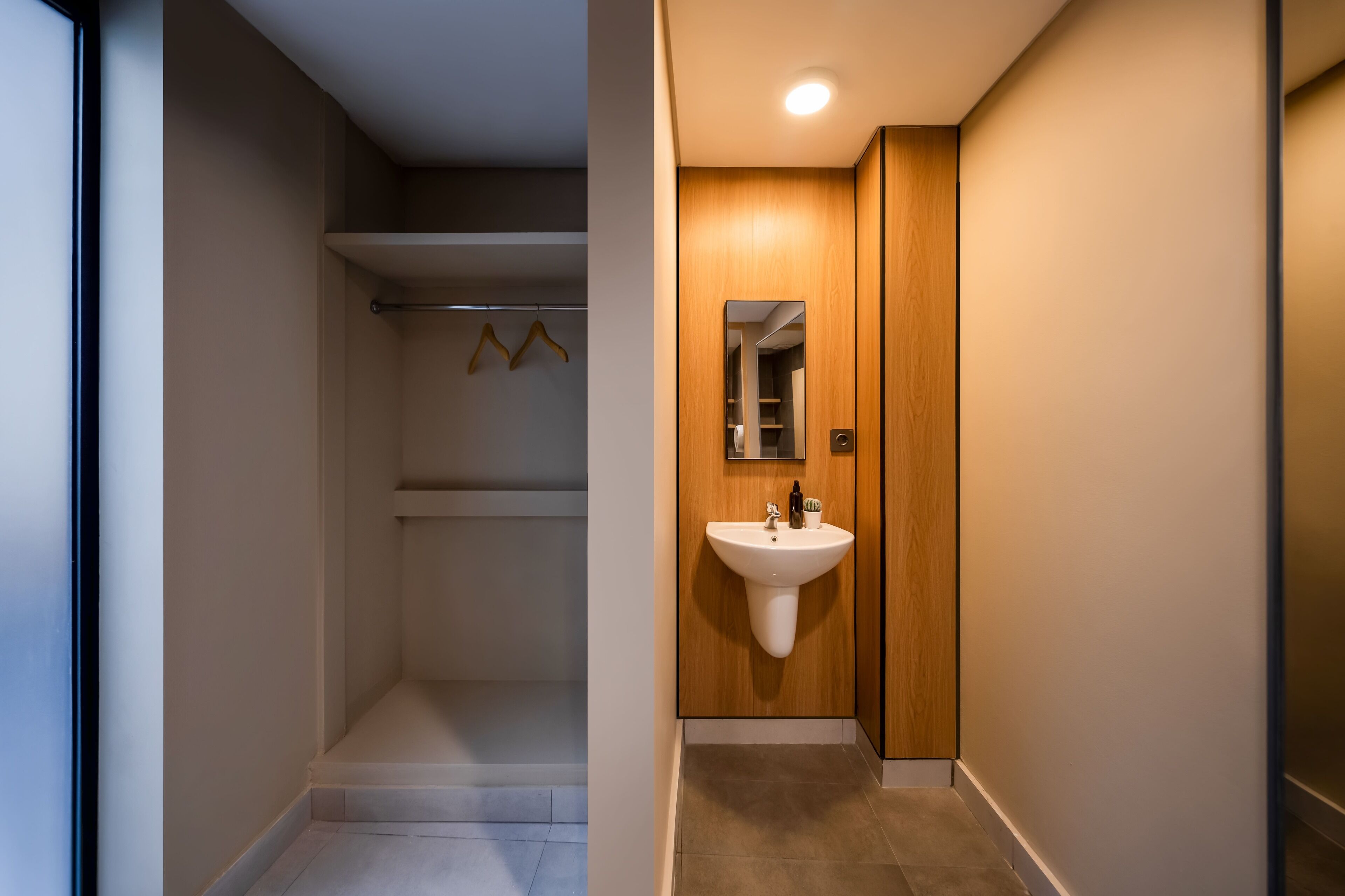 A narrow hallway with a wooden door on the right, a white sink, and a mirror above it.