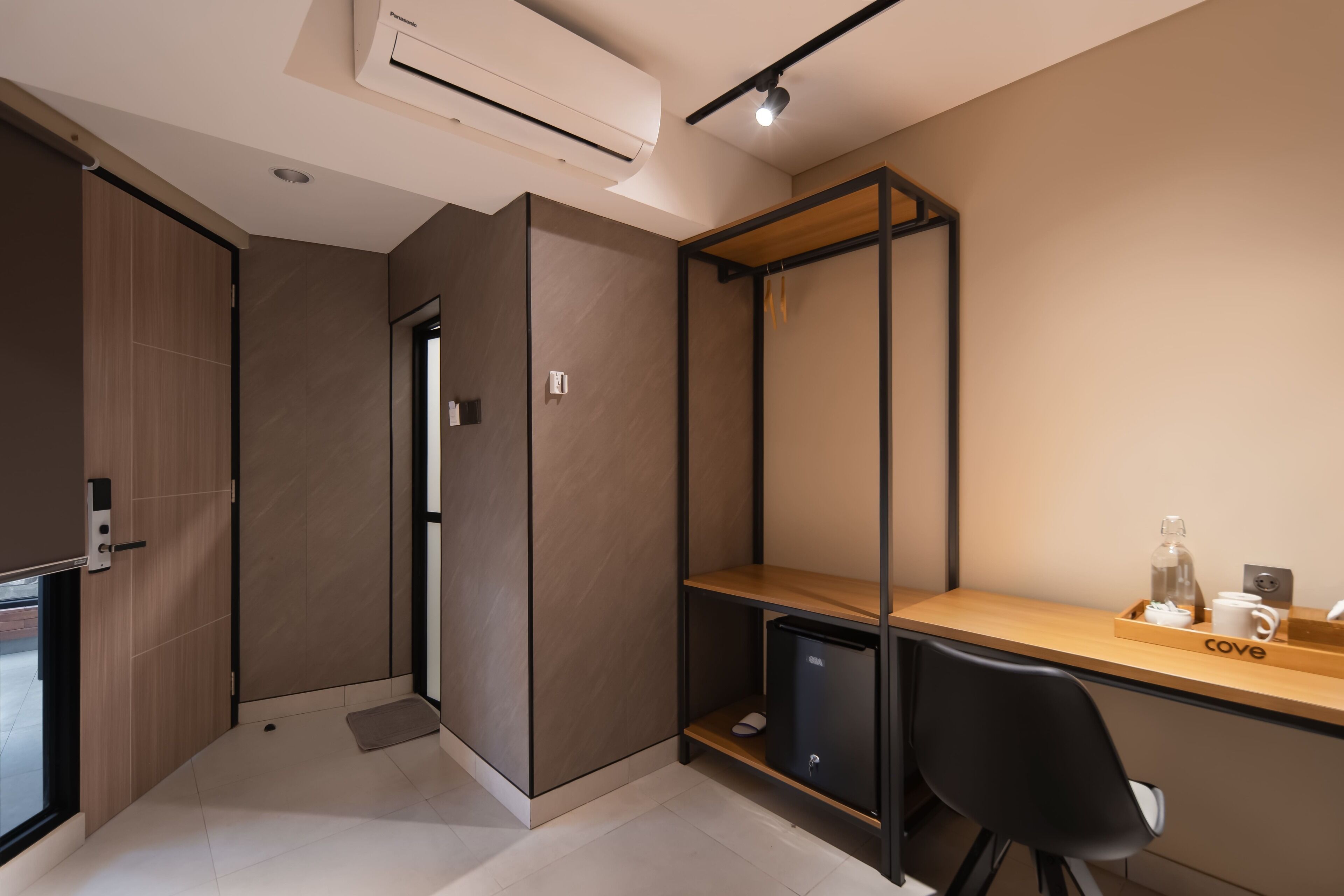 A modern room with a wooden desk, a black chair, a small black cabinet, and a built-in shelf unit.