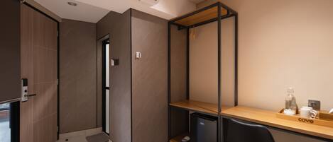 A modern room with a wooden desk, a black chair, a small black cabinet, and a built-in shelf unit.