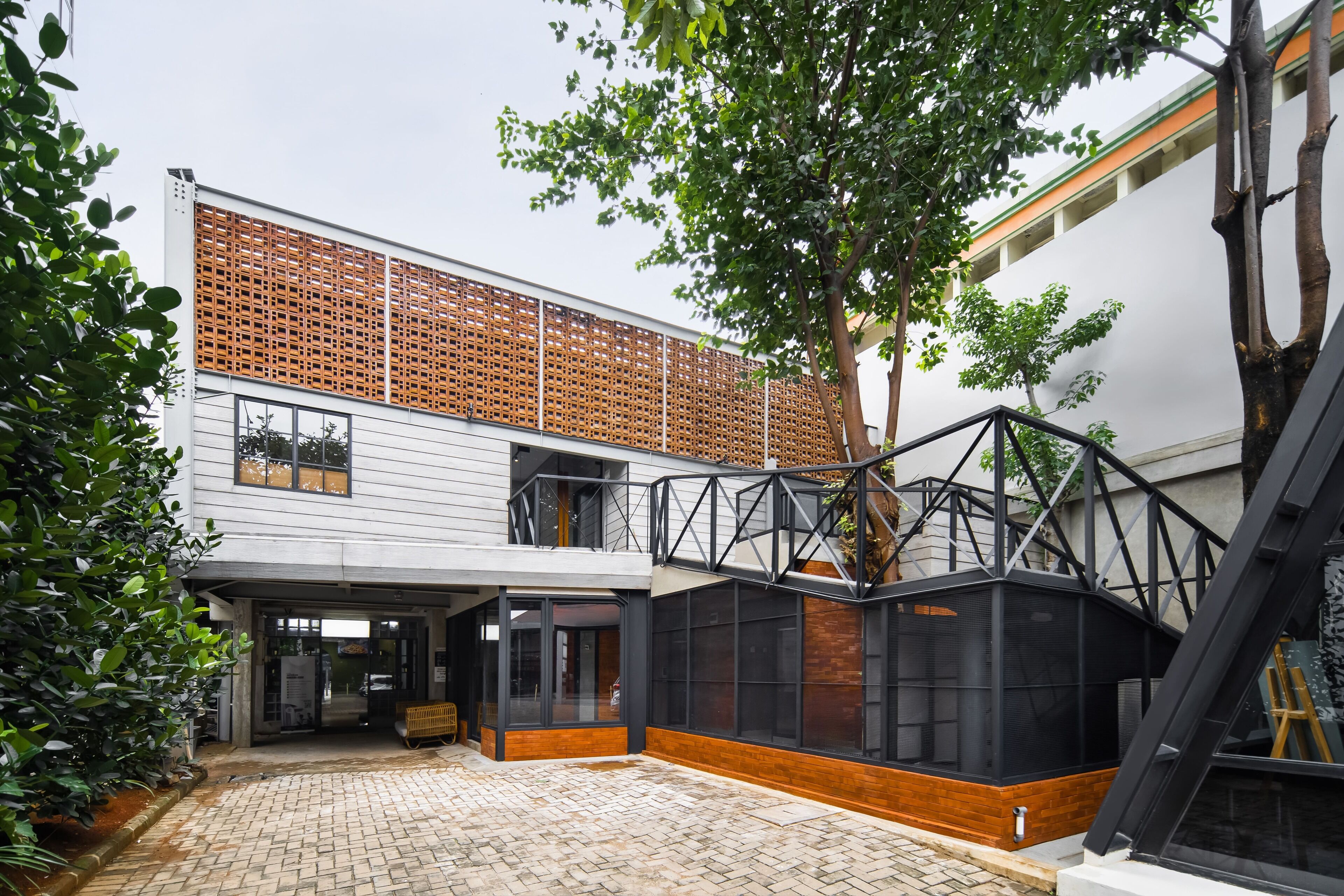 Um edifício moderno com pátio de tijolos, janelas amplas e cerca de madeira.