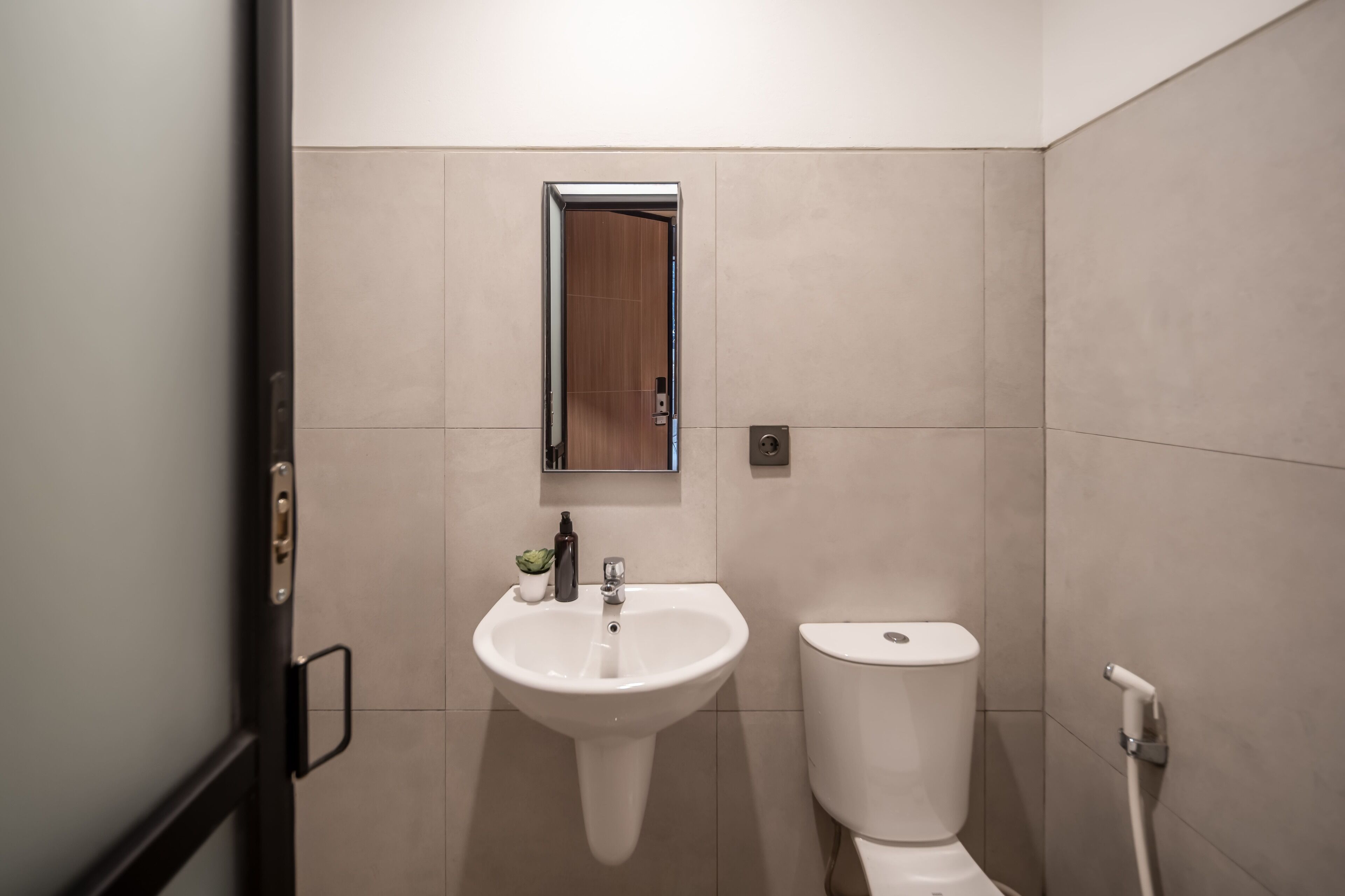 Un baño moderno con un lavabo blanco, un inodoro y un espejo sobre el lavabo.