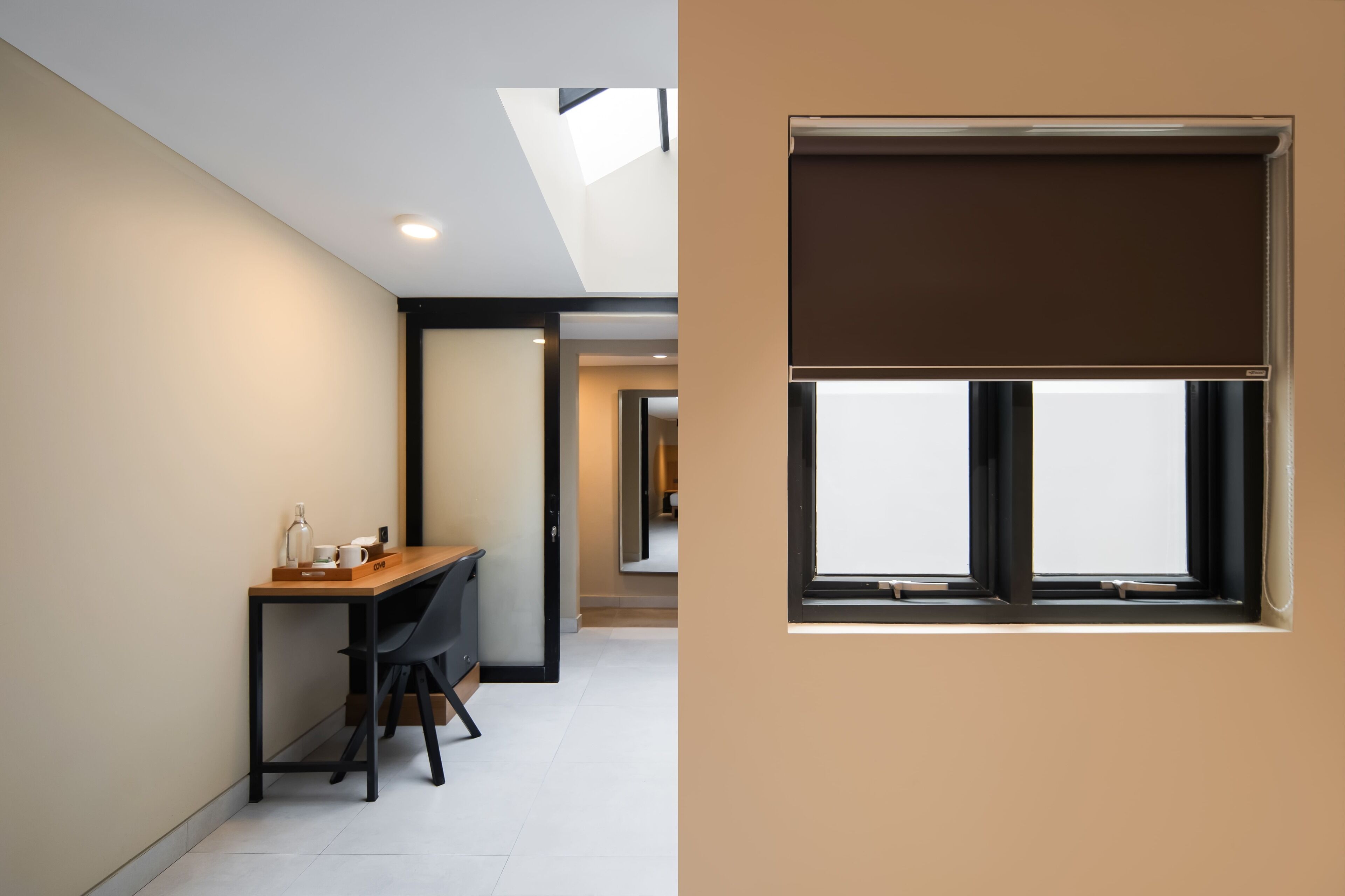 A modern room with a desk, chair, and a large window with a blind.