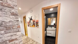 A hallway with a rustic brick wall, a wooden door frame, and a tiled floor.