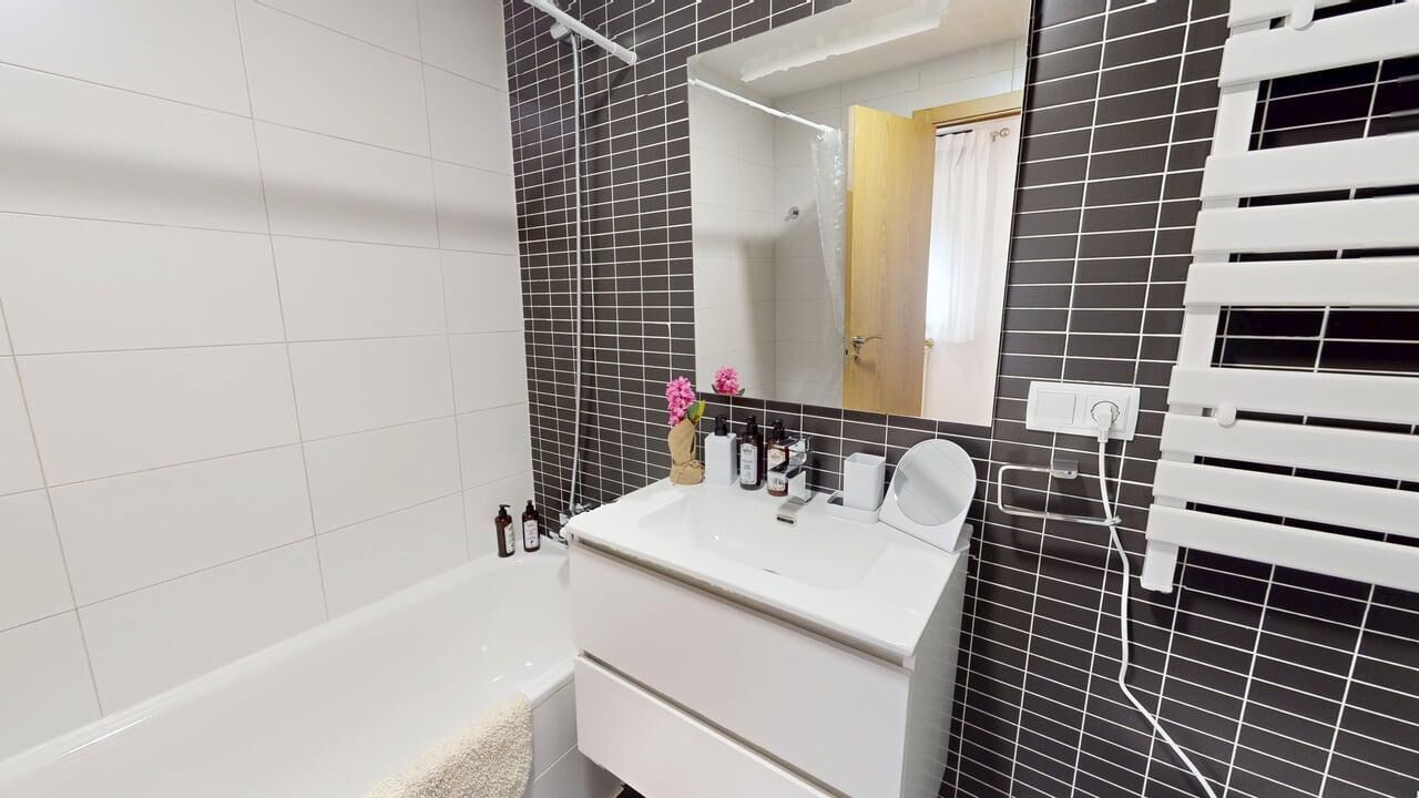 A bathroom with a white sink, mirror, and a shower area.
