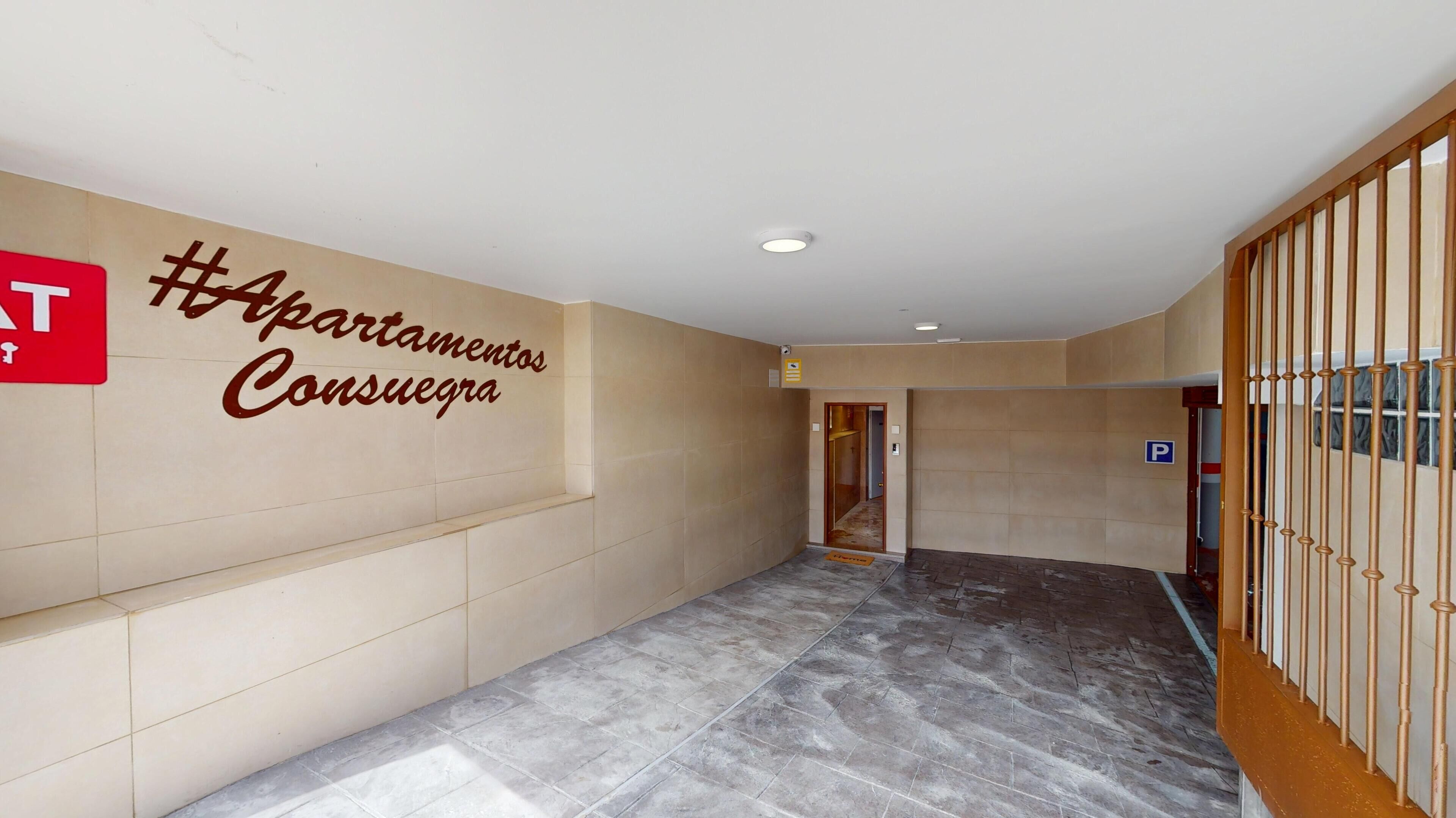 Un couloir avec une pancarte indiquant « #Apartamentos Consuelo » et un panneau de signalisation pour le stationnement.