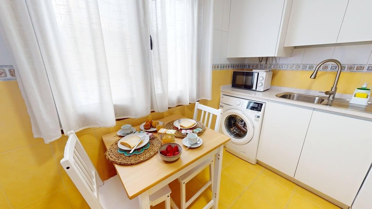 Cocina compacta con lavadora, microondas y lavabo.