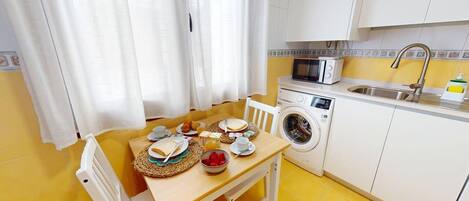 Cocina compacta con lavadora, microondas y lavabo.