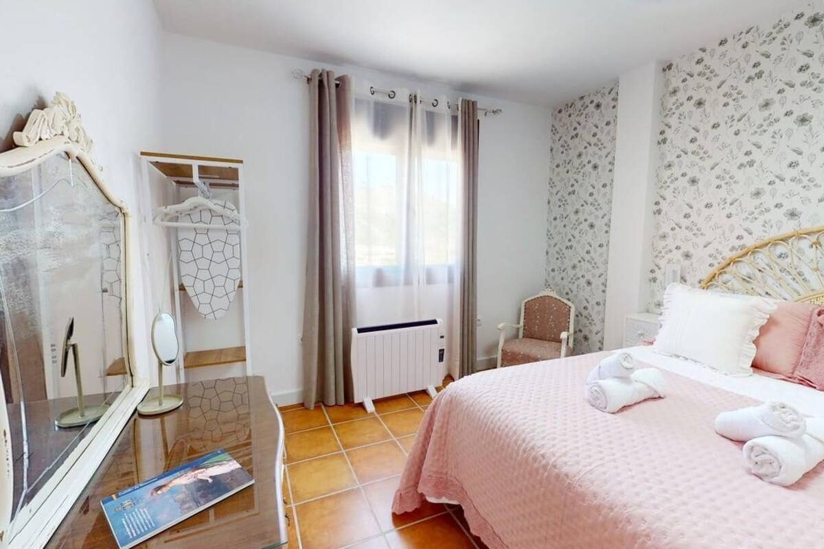 A bedroom with a bed, a chair, a wardrobe, and a mirror.