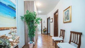 A hallway with a potted plant, two wooden chairs, a painting, and a framed picture on the wall. - La Sciumara With Beach Access (Arzachena)