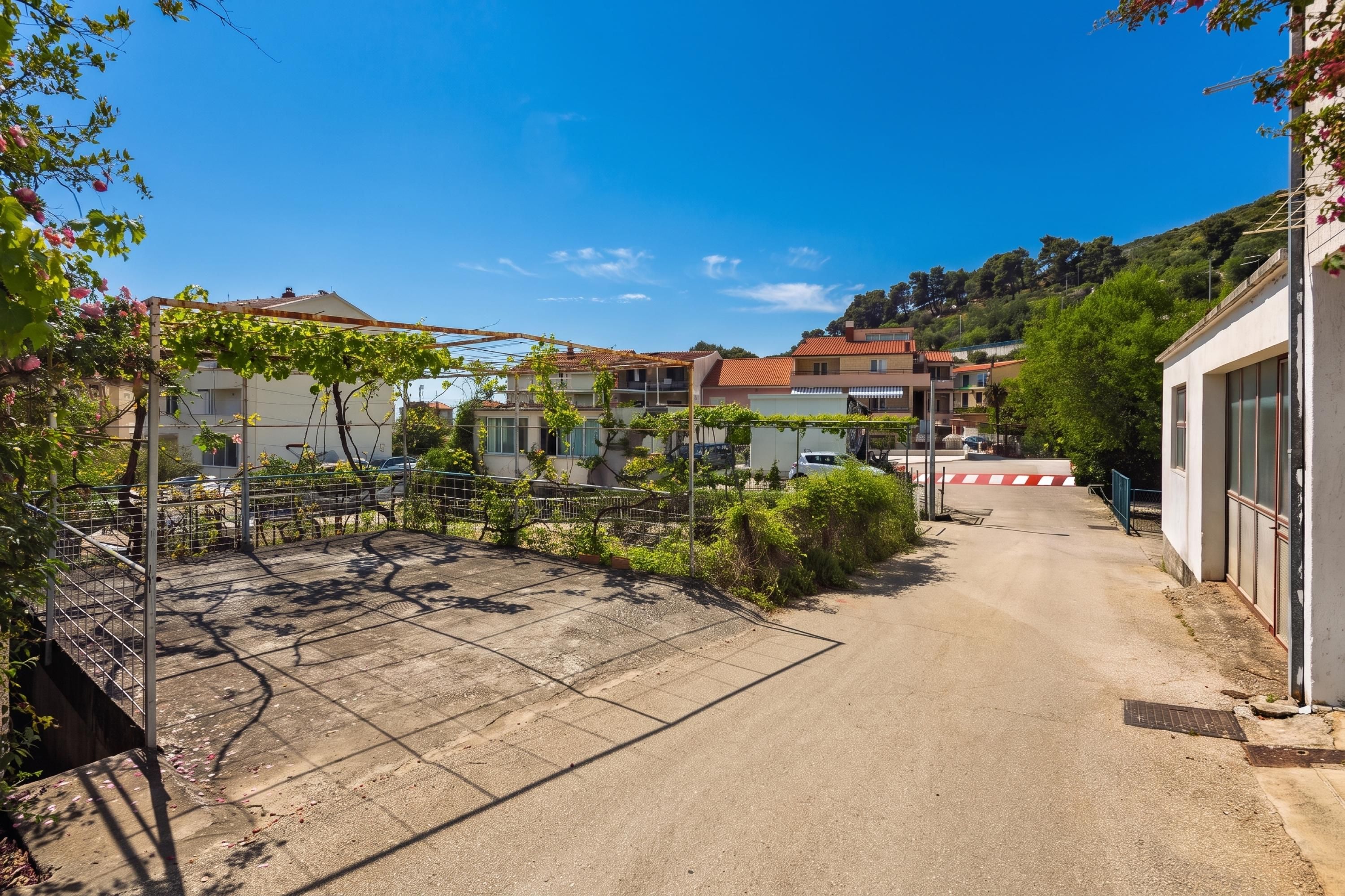 A residential street with houses, a gated entrance, and a clear sky.