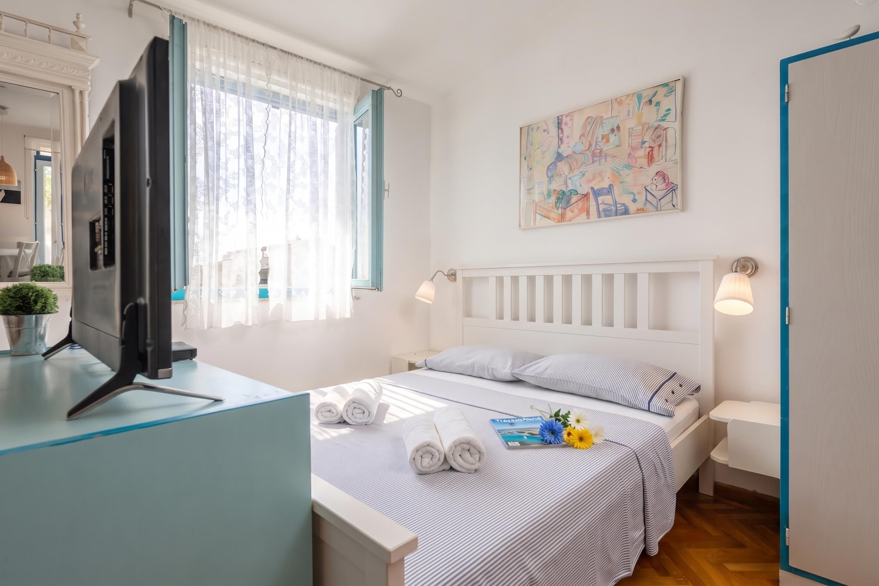 A hotel room with a bed, a desk, a television, and a window with curtains.