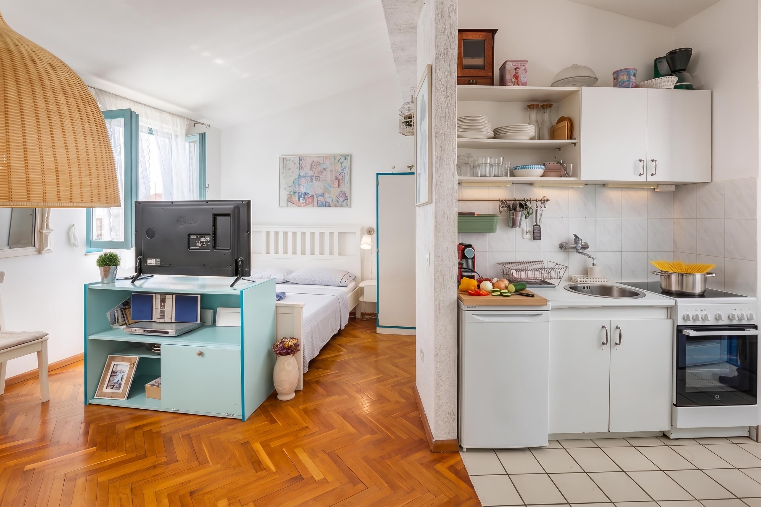 A compact living space with a kitchenette, a bed, a television, and a dining area.