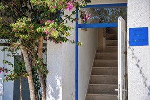 Eine Treppe führt zu einem Hauseingang einer Wohnung, dessen blauer Rahmen und ein Schild darauf hinweisen, dass es sich um eine Wohnung handelt.