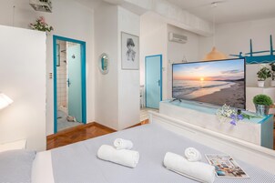 Una habitación de hotel con cama, televisión, baño y vista a la playa.