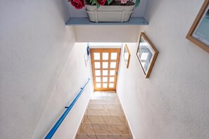 En trappa med ett blått ledstång som leder upp till en trädörr med ett rutmönster.