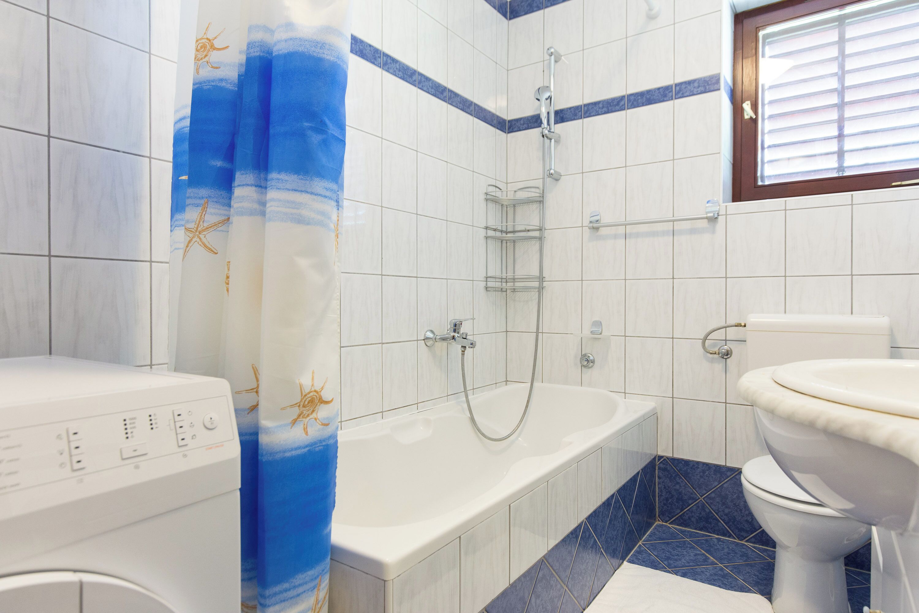 Un baño con bañera, inodoro y lavadora.