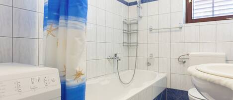 Un baño con bañera, inodoro y lavadora.