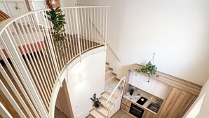 A modern interior with a spiral staircase, a kitchen area, and a dining space. - BONA NOVA – Puglia Living (Massafra)