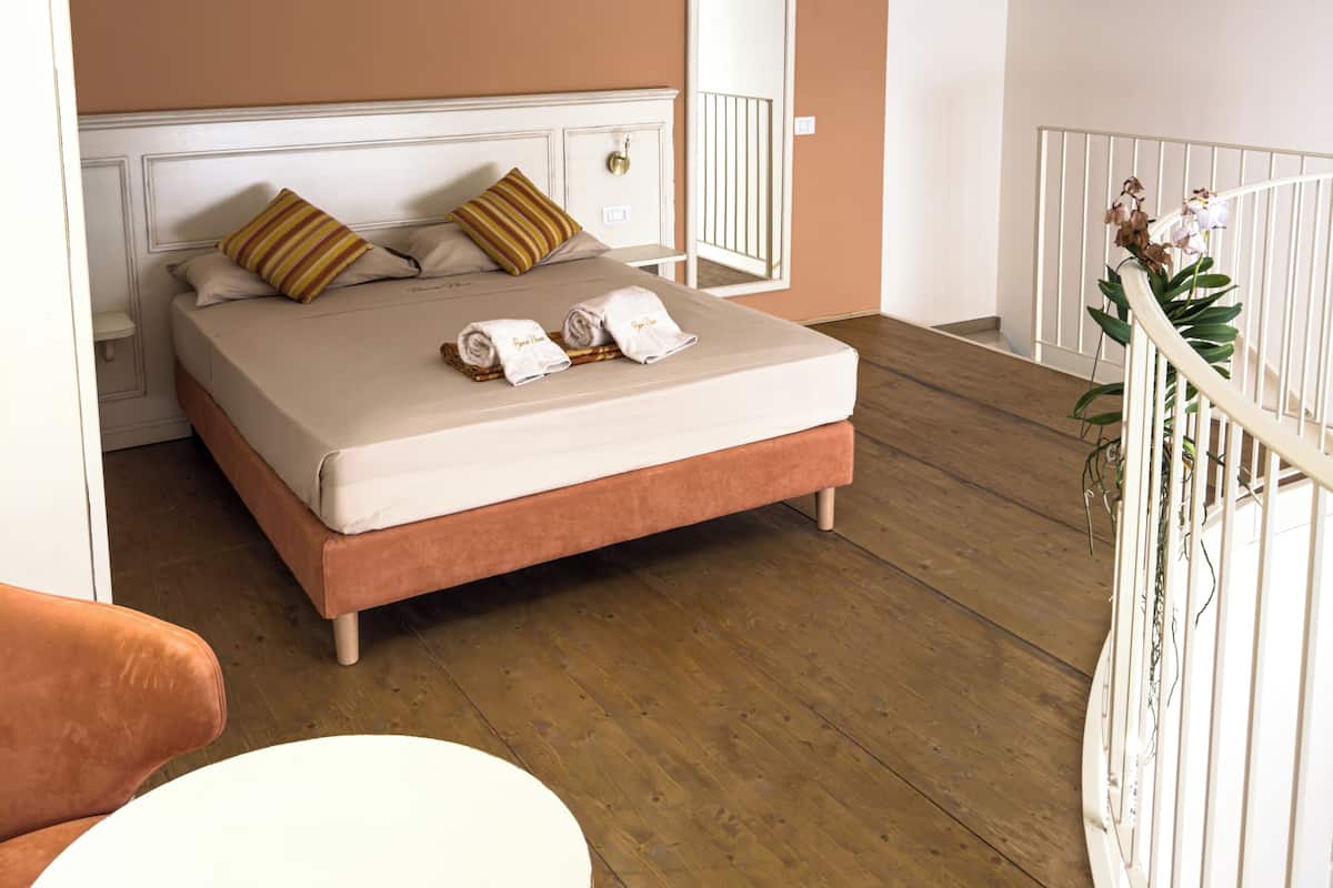 Ein Schlafzimmer mit Bett, Nachttisch, Stuhl und einem Balkon mit Geländer.