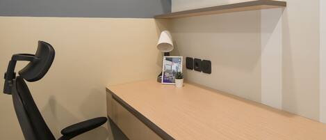 A modern office desk with a chair, a lamp, a small potted plant, and a brochure.