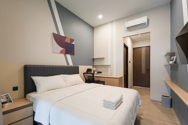 A modern hotel room with a large bed, a desk, a chair, and a TV. - Cove Equatoria (Curug)