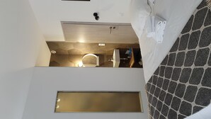 A hotel room with a bed, a small bathroom, and a window. - Just 10 minutes from the town center, this cocooning studio is sure to make your stay a pleasant one! (Mulhouse)