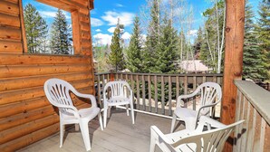 A wooden cabin with a balcony featuring white plastic chairs and a view of tall trees. - Lemmon Lodge #30 – Lake Access with private sandy beach (Grand Lake)