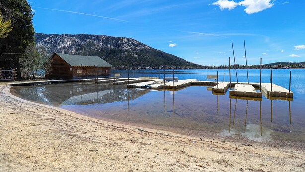 A wooden cabin by a calm lake with a dock and a sandy beach. - Lemmon Lodge #30 – Lake Access with private sandy beach (Grand Lake)