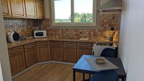 Une cuisine compacte avec des meubles en bois, un four à micro-ondes et une fenêtre donnant sur un espace verdoyant.