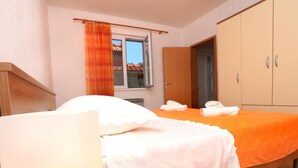 Un dormitorio con cama, un armario de madera, una ventana con cortinas y una puerta.