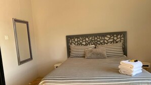 A hotel room with a bed, striped bedding, a decorative headboard, a mirror, and a stack of towels.