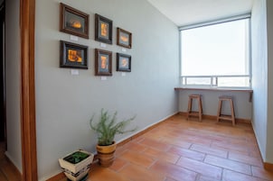 Una habitación con suelo de baldosas, una planta en maceta y cuatro cuadros en la pared.