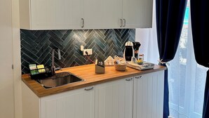 Una cocina moderna con armarios blancos, un salpicadero de baldosas tipo espiga, encimera de madera y alfombra negra.