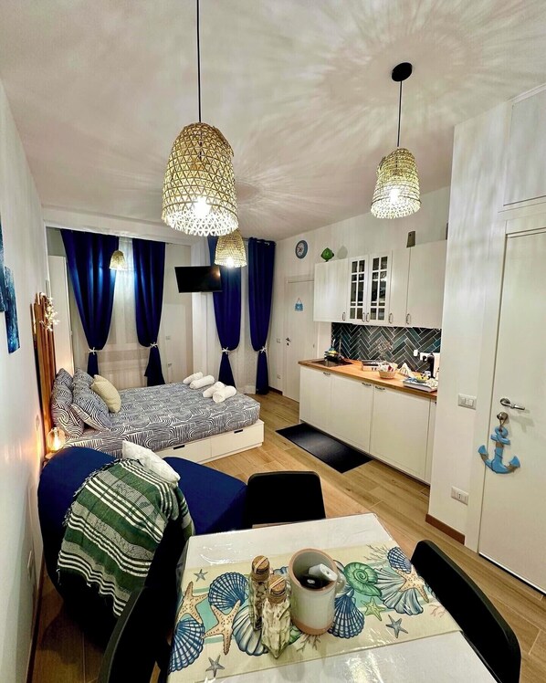 A compact living space with a kitchenette, a dining area, and a bed with patterned bedding.