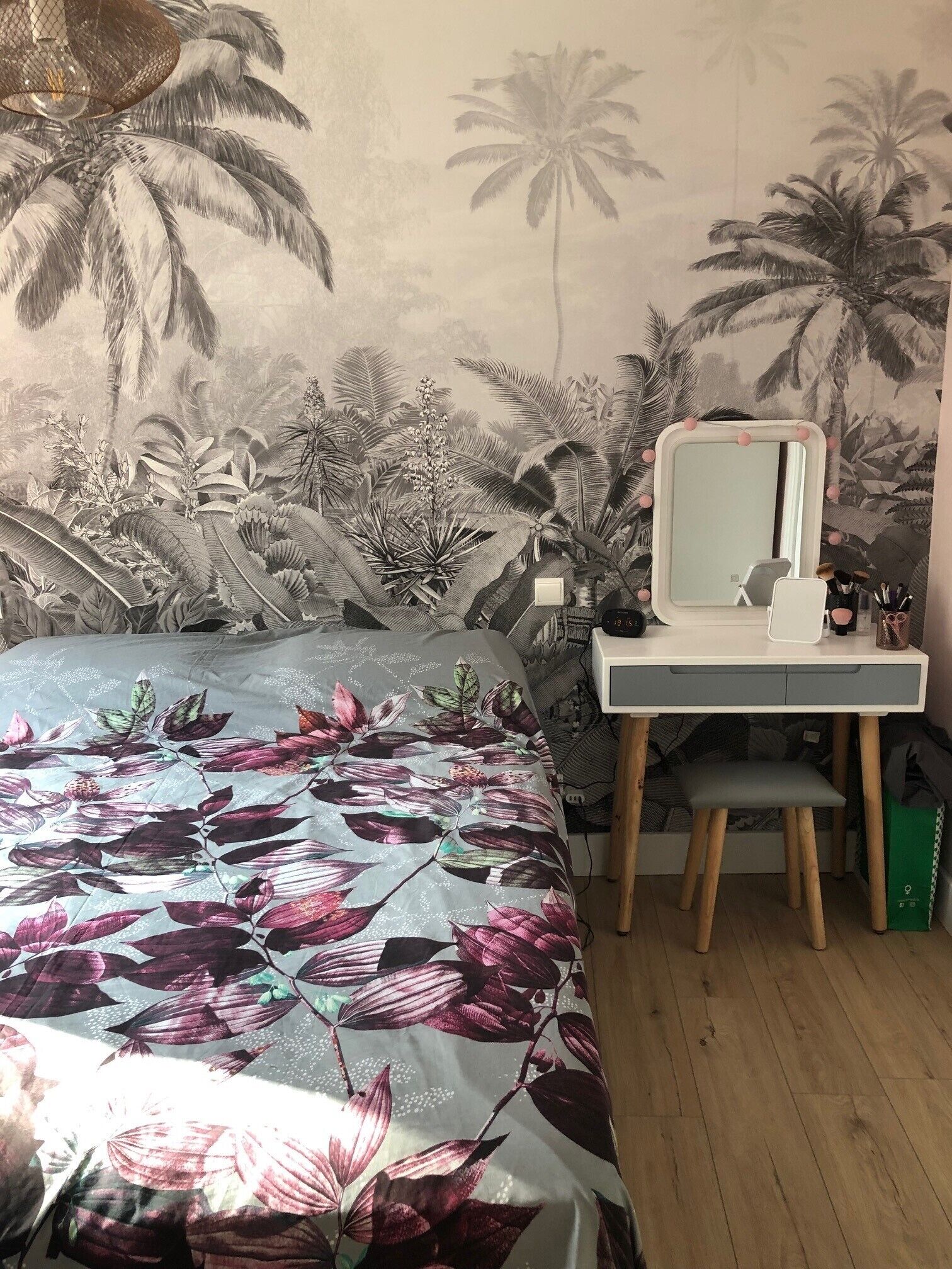 A bedroom with a bed, a desk, and a mirror.