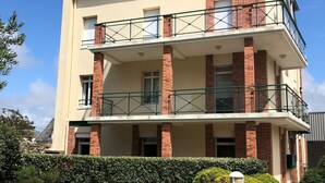 A multi-story residential building with a flat roof, brick and plaster exterior, and a small balcony on the second floor. - Granville, 50m from the sea, on the garden level, nice and cosy apartment-terrace for 2 persons (Granville)