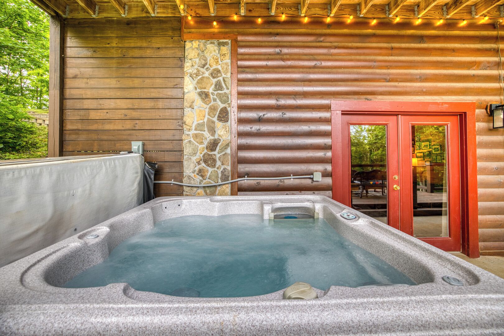 Ein Whirlpool in einer Blockhütte mit einer Steinwand und Holzbalkendecke.