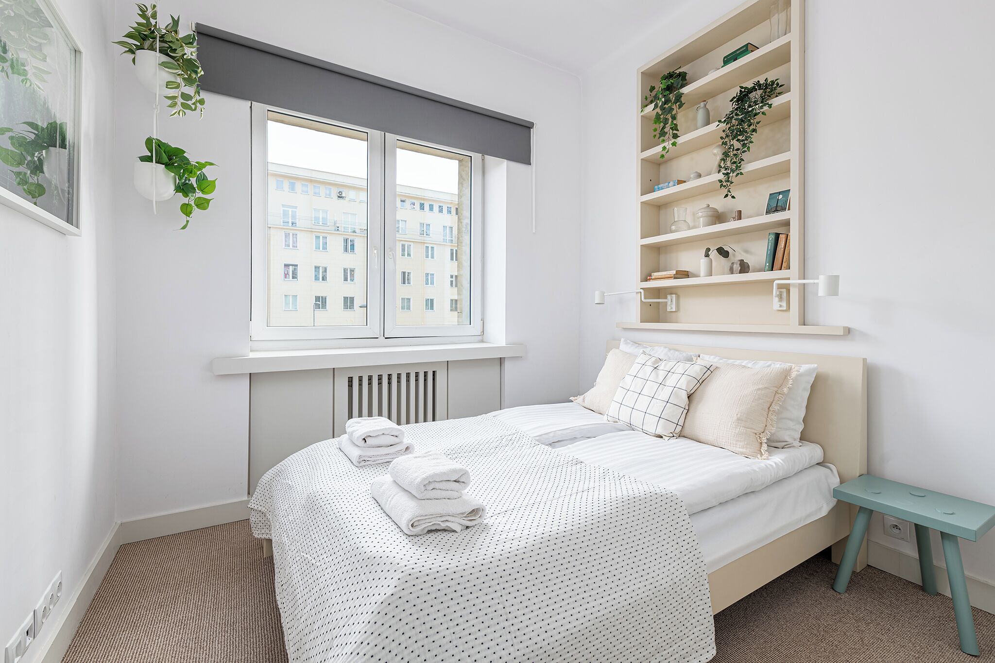 A neatly arranged bedroom with a bed, bedside table, and a window with blinds.